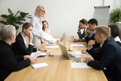 Woman talking to man sternly in big meeting - Wrongful Termination